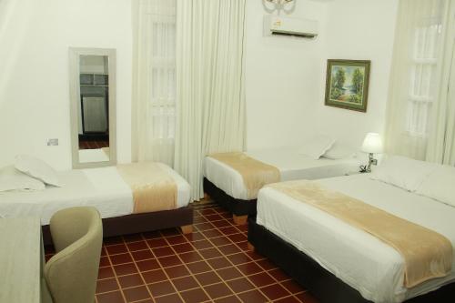 a hotel room with two beds and a mirror at Hotel Casa Colonial in Barranquilla