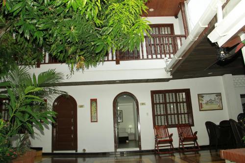 a building with two chairs and a hallway with trees at Hotel Casa Colonial in Barranquilla