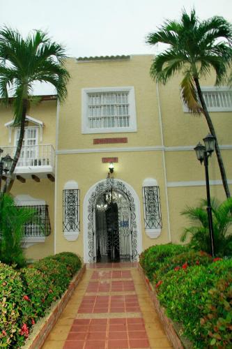a yellow building with a gate and palm trees at Hotel Casa Colonial in Barranquilla