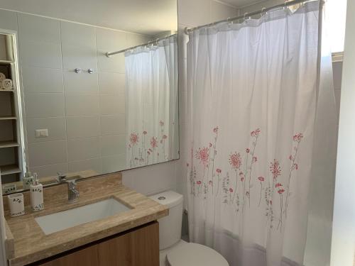 y baño con aseo y cortina de ducha. en DEPARTAMENTO EN RESORT LAGUNA DEL MAR en La Serena