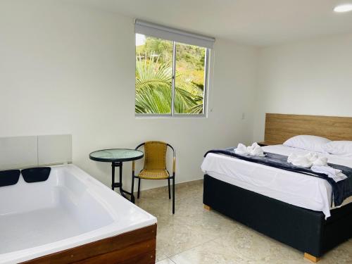 a bedroom with a tub and a bed and a table at La Madriguera in Guatapé