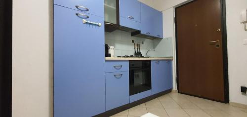 una pequeña cocina con armarios azules y una puerta en Sweet Home en Chiaravalle