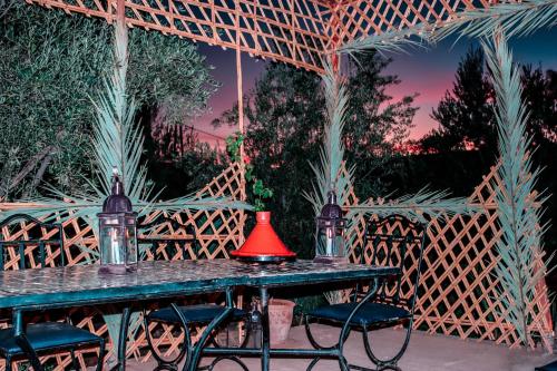 een tafel met stoelen en een rode lamp erop bij Gîte Ait lmaalam chez Ahmed in Skoura