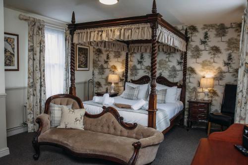 1 dormitorio con cama con dosel y sofá en The George Inn en Warminster