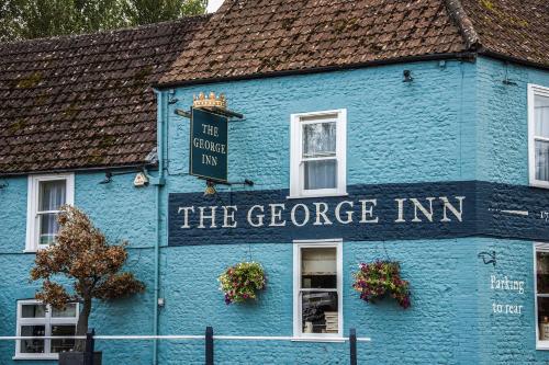 a blue building with a sign that reads the george inn at The George Inn in Warminster