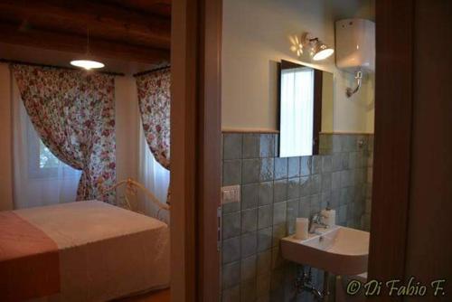 Schlafzimmer mit einem Bett, einem Waschbecken und einem Spiegel in der Unterkunft L' Antico Pozzo Country House in Monsampietro Morico