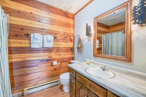 uma casa de banho com paredes de madeira, um lavatório e um espelho. em Valley of The Pines Chalet em Red River