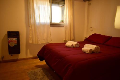 1 dormitorio con 2 camas rojas y toallas. en El Luminoso 11 en La Plata