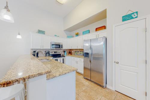 a kitchen with white cabinets and a stainless steel refrigerator at Morgan Shores in Port Aransas