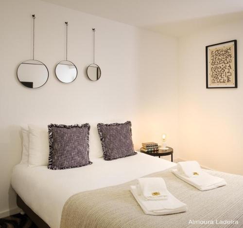 a bedroom with a bed with two mirrors on the wall at Almoura Ladeira in Évora