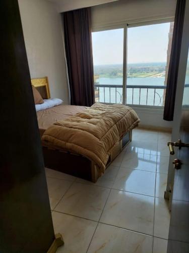 ein Schlafzimmer mit einem Bett und einem großen Fenster in der Unterkunft Stunning river view from a spacious 3-Bedroom Apt. in Kairo
