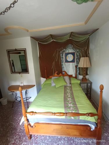 a bedroom with a wooden bed with a green comforter at Hotel Posada Spa Antigua Casa Hogar in Taxco de Alarcón