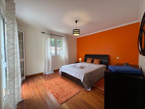 Un dormitorio con una pared de color naranja y una cama. en Briola by AnaLodges, en São Vicente