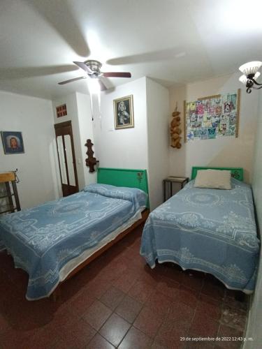 two beds in a room with a ceiling fan at Hotel Posada Spa Antigua Casa Hogar in Taxco de Alarcón