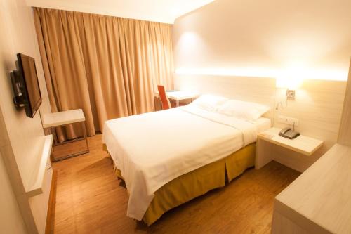 a hotel room with a white bed and a desk at Hotel Malaysia in George Town