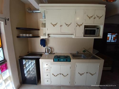 a small kitchen with white cabinets and a sink at Hotel Posada Spa Antigua Casa Hogar in Taxco de Alarcón