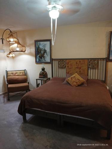 a bedroom with a large bed and a chair at Hotel Posada Spa Antigua Casa Hogar in Taxco de Alarcón