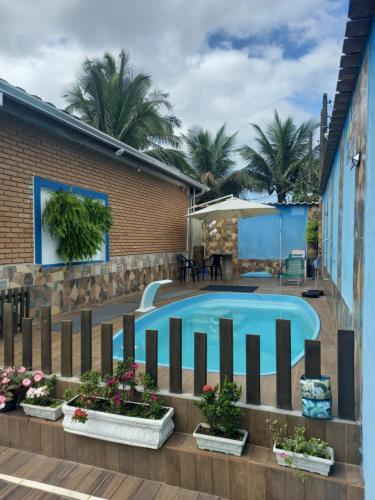 a swimming pool with potted plants next to a building at Chalé do Tio Beto - Caraguatatuba in Caraguatatuba