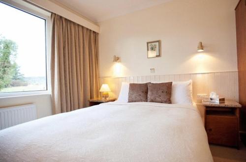 a bedroom with a large white bed with a window at Kenmare House in Kenmare