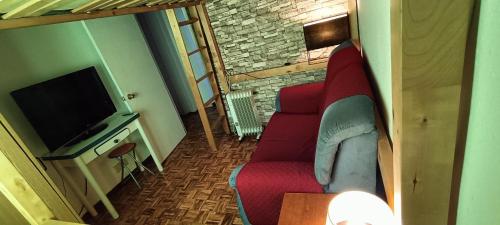 ein Wohnzimmer mit einem roten Sofa und einem TV in der Unterkunft La Doñita2 in Madrid