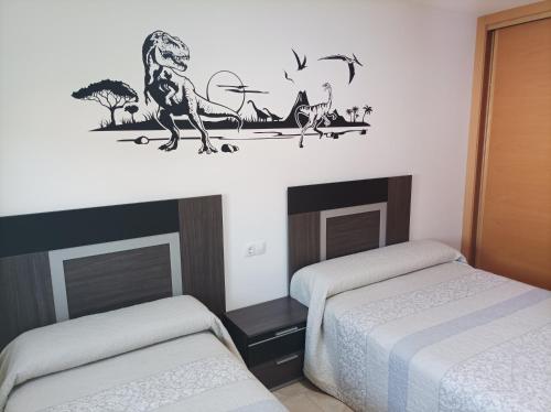 una habitación con 2 camas y una pegatina de mono en la pared en Casa Dinorural, en El Castellar