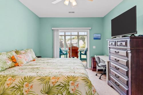 a bedroom with a bed and a dresser with a flat screen tv at Coral Reef Retreat in Sunset Beach