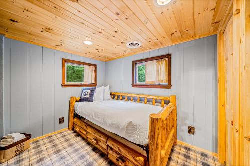 ein Schlafzimmer mit einem Bett in einem Zimmer mit Holzdecken in der Unterkunft Minerva's Log Cabin Gem in Minerva