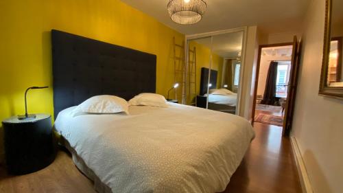 um quarto com uma grande cama branca e uma grande cabeceira de cama. em Paris Coeur Saint Germain Standing em Paris