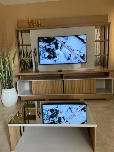 a living room with two televisions on a entertainment center at Apartamentos Avenida in Praia