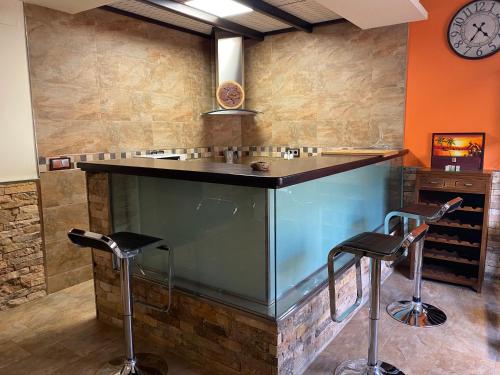 a bar with two stools and a clock on the wall at Casa Rural La Sureña in Ossa de Montiel