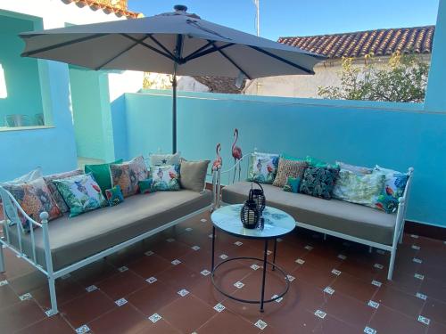 eine Terrasse mit 2 Sofas und einem Tisch mit einem Sonnenschirm in der Unterkunft Luz Los Romeros in Los Romeros