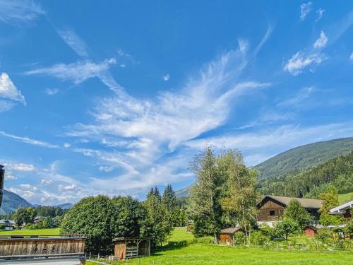 a green field with trees and a blue sky at Krammer XL in Neukirchen am Großvenediger