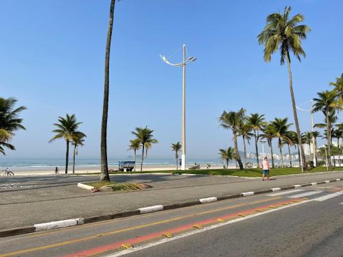 a person walking down a street with palm trees and the beach at Acomodações Tio Will in Guarujá