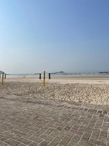 a beach with some yellow poles in the sand at Acomodações Tio Will in Guarujá