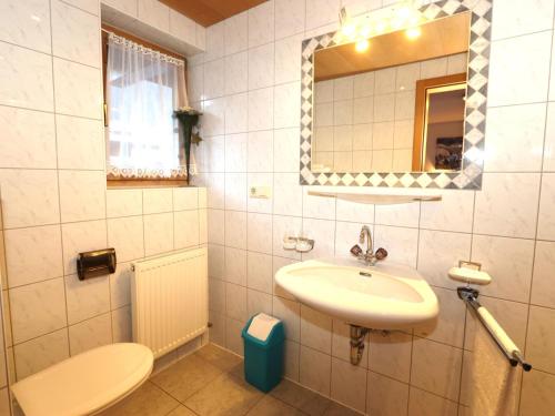 ein Badezimmer mit einem Waschbecken, einem WC und einem Spiegel in der Unterkunft Haus Daheim I in Winkle