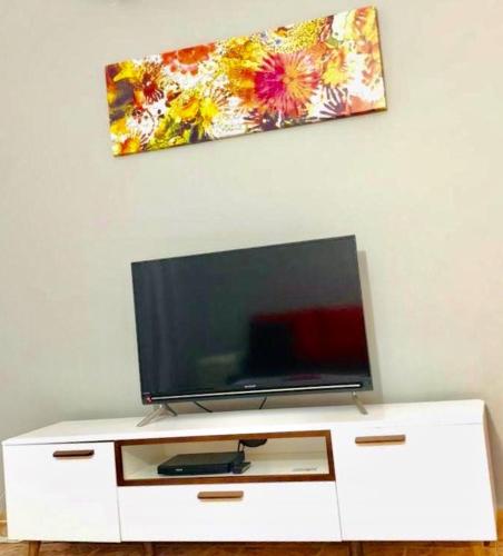 a flat screen tv sitting on top of a white cabinet at Sonnige Ferienwohnung mit Wifi in Flic-en-Flac