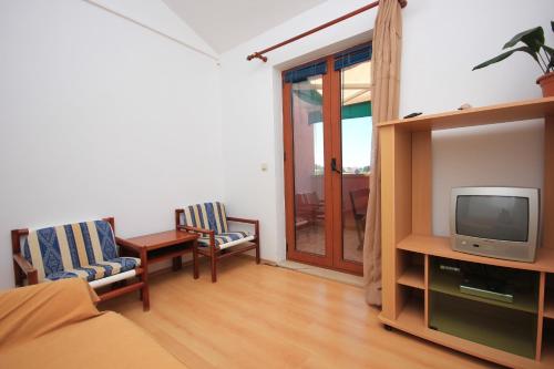 uma sala de estar com televisão e duas cadeiras em Apartment Ilovik 8069a em Ilovik