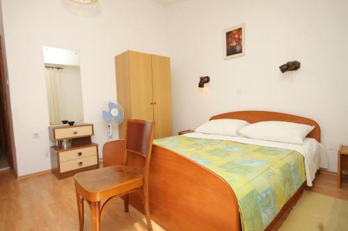 a bedroom with a bed and a chair and a table at Triple Room Pasman 8223e in Pašman