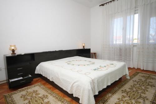 een slaapkamer met een bed met een witte deken bij Apartments with a parking space Ugljan - 8404 in Ugljan