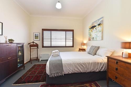 a bedroom with a bed and a dresser and a window at Summerfield Cottage Hunter Valley in Branxton