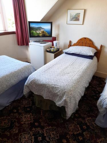 a hotel room with two beds and a flat screen tv at Abacus Central Guest House in Aberdeen