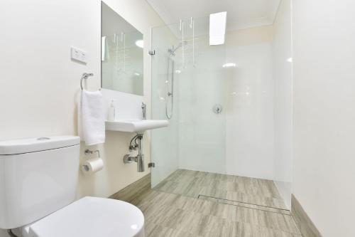 a white bathroom with a toilet and a shower at Summerfield Cottage Hunter Valley in Branxton
