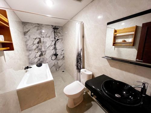 ein Badezimmer mit einem Waschbecken, einem WC und einer Badewanne in der Unterkunft Bali 85 Beach Inn in Padangbai