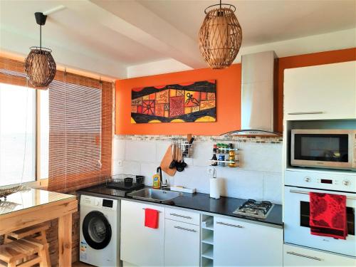 a kitchen with an orange wall and a sink at CLEMARA EVASION in Schœlcher