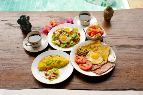 une table avec des assiettes de petit-déjeuner et deux tasses de café dans l'établissement Satya House Ubud, à Ubud
