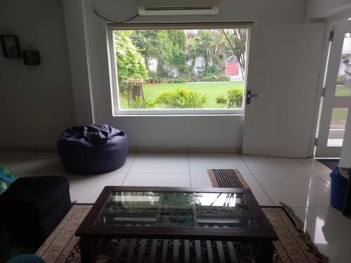 a living room with a glass coffee table in front of a window at Green Serene Abode in Meerut