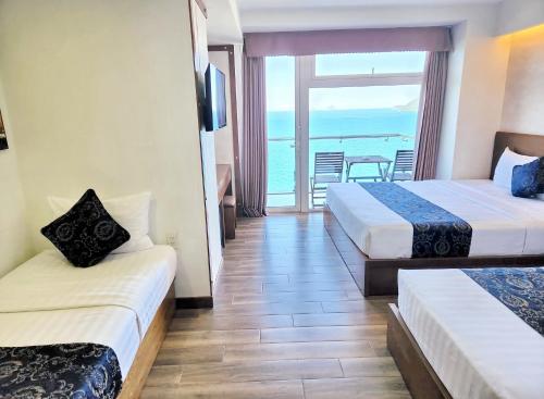 two beds in a room with a view of the ocean at Saphia Hotel Nha Trang in Nha Trang