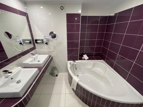 a purple and white bathroom with a tub and sink at Hôtel Amazonia Cayenne Centre in Cayenne