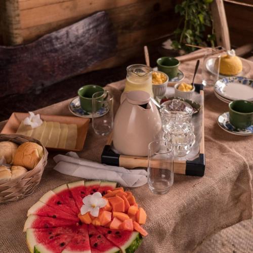 a table with fruit and cheese and a jug of milk at Flor da Aldeia Eco Hospedaria in Camaçari