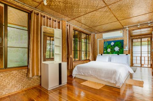 a bedroom with a bed and some windows at Hin Khong Villa - a tropical surprise in Ban Huai Sai